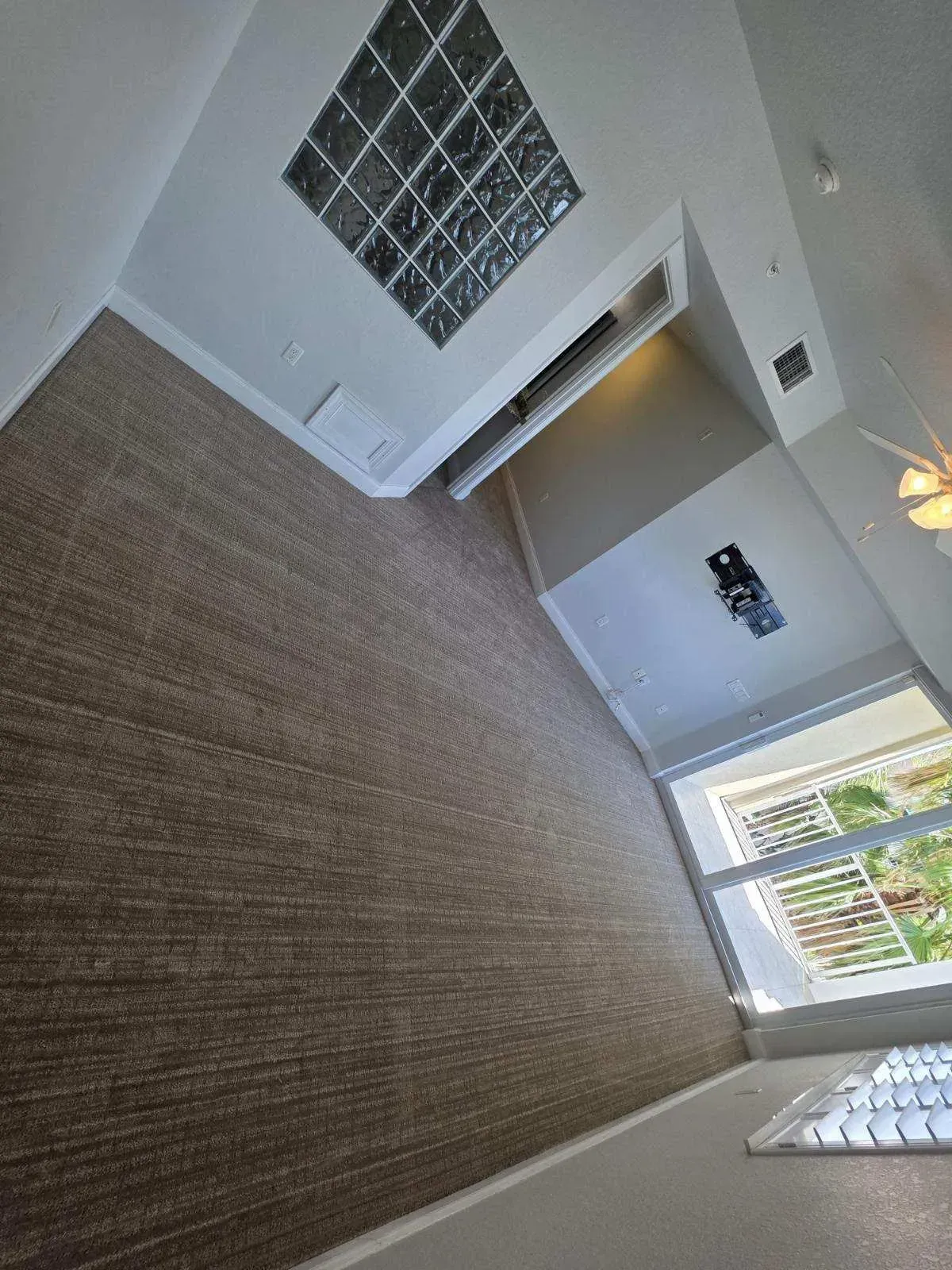 Room with brown carpet, glass block window, and view of the outdoors.