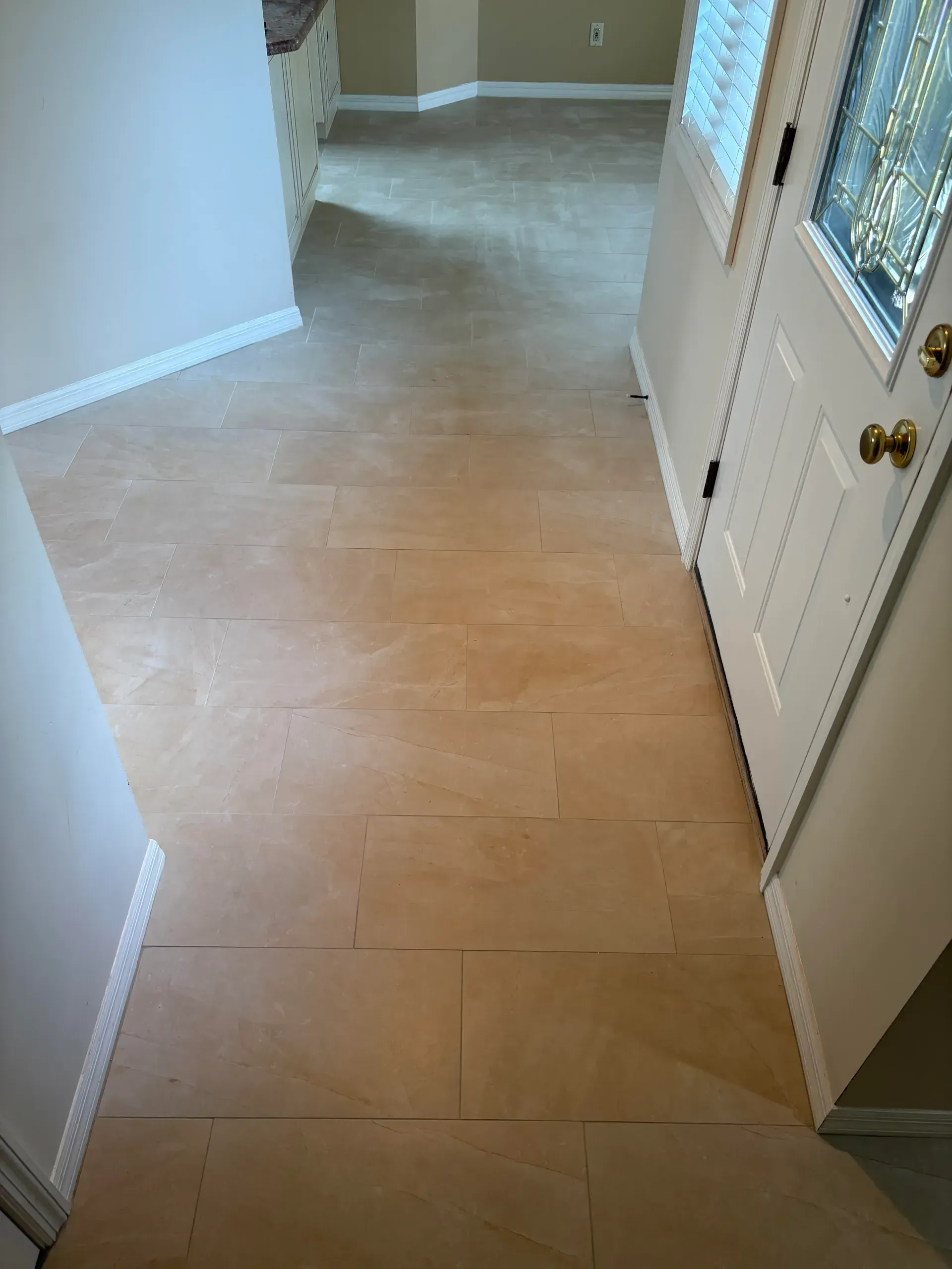 View of a hallway with bare plywood flooring, white door, and off-white walls.