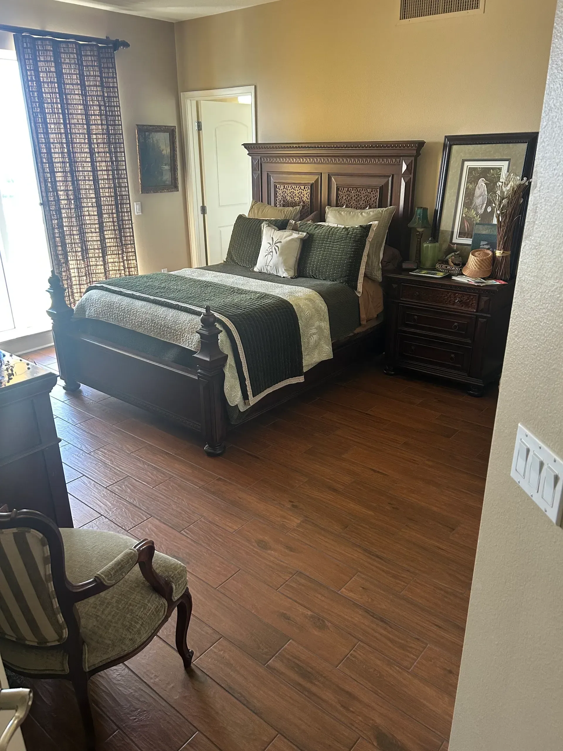 Bedroom with dark wood furniture, green and white bedding, and hardwood floors.