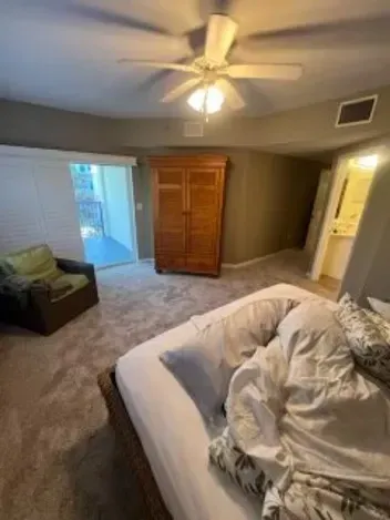 Bedroom with a bed, armoire, armchair, and sliding door leading to a patio.
