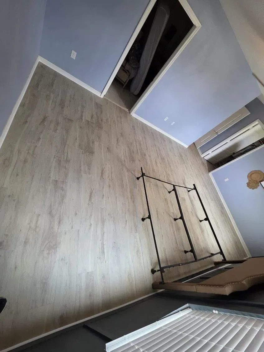 View from above of a room with light wood-look flooring, light blue walls, and a metal clothing rack.