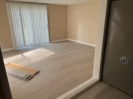 Empty room with tan walls, light gray floor, and sliding glass door with closed blinds.