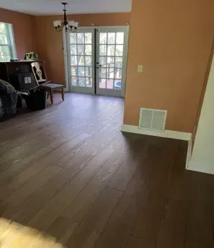 Living room with hardwood floors, peach walls, and French doors leading to outdoors.