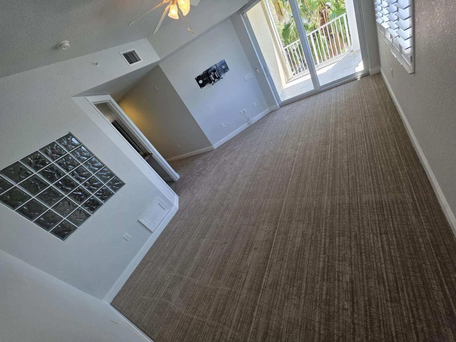 Room with brown carpet, glass block window, and view of the outdoors.