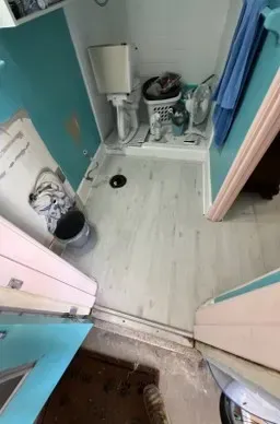 Small bathroom with toilet, sink, laundry basket, and shower curtain. Blue and white colors.