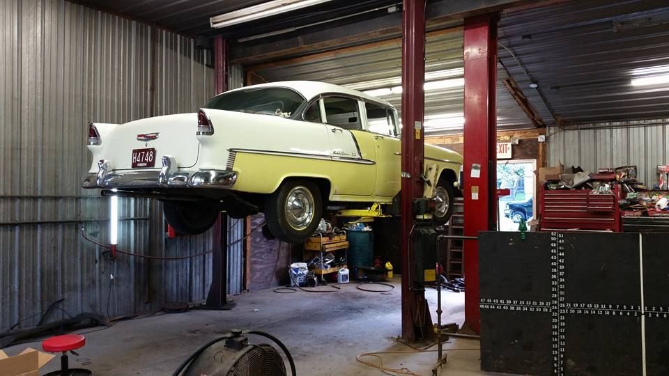 A yellow car is on a lift in a garage