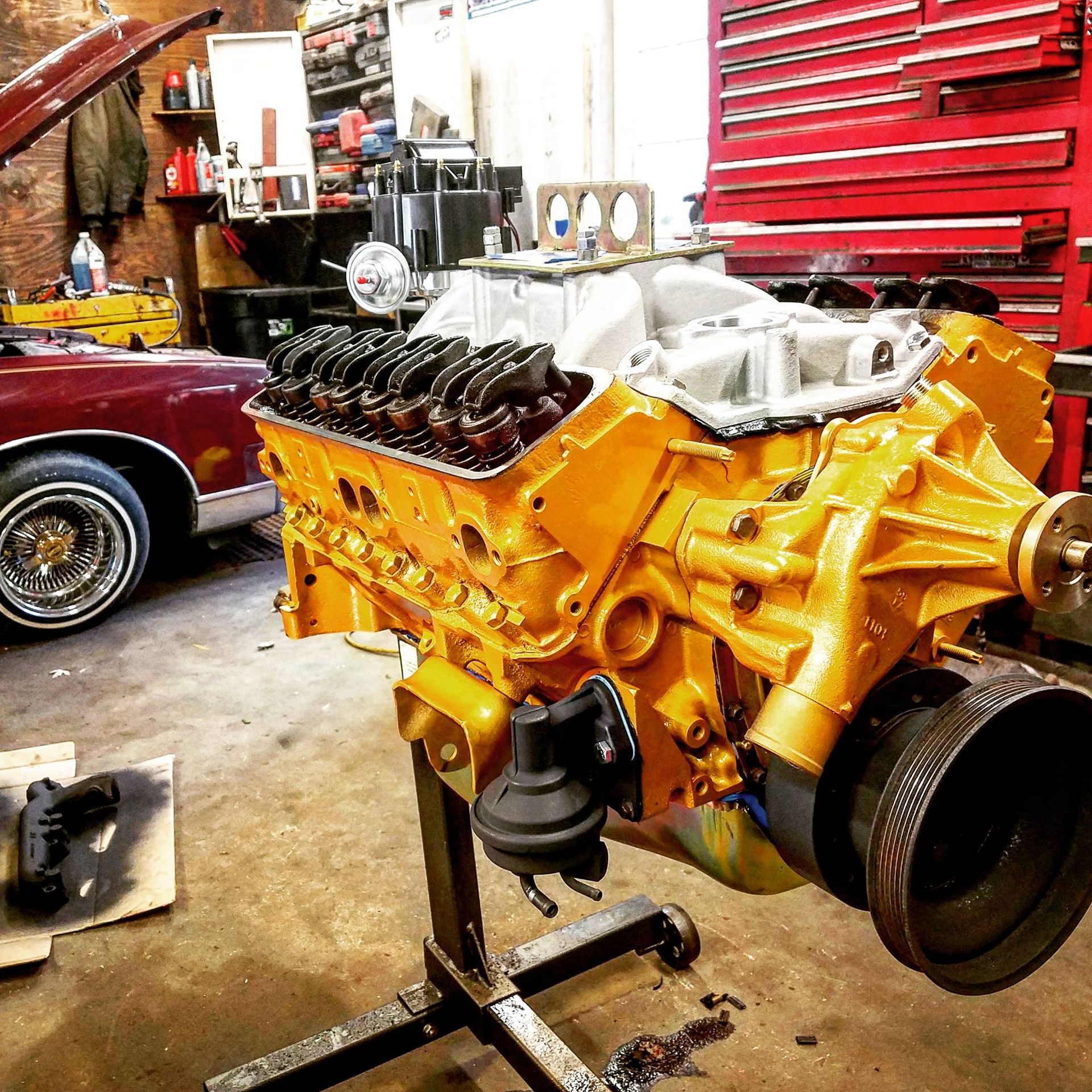 A yellow engine is sitting on a stand in a garage