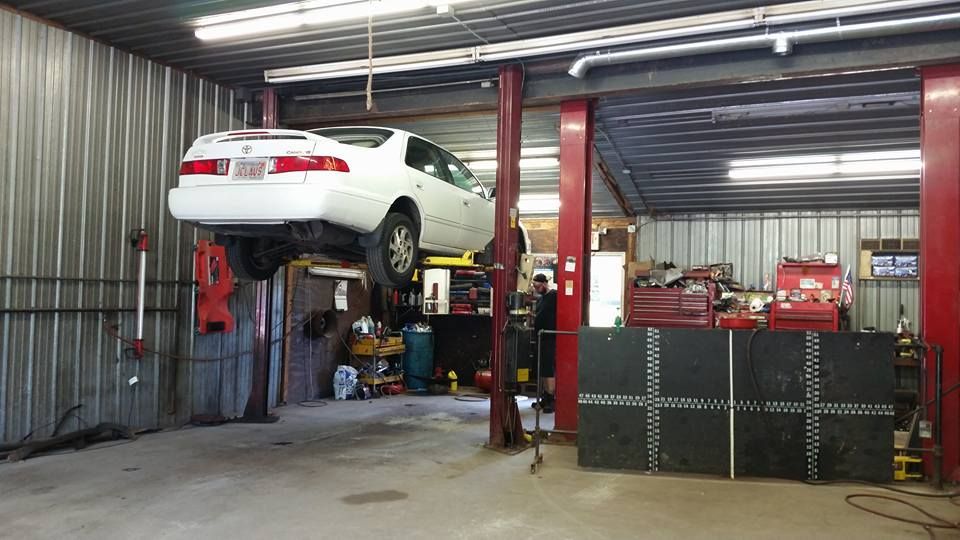 A white car is sitting on a lift in a garage.