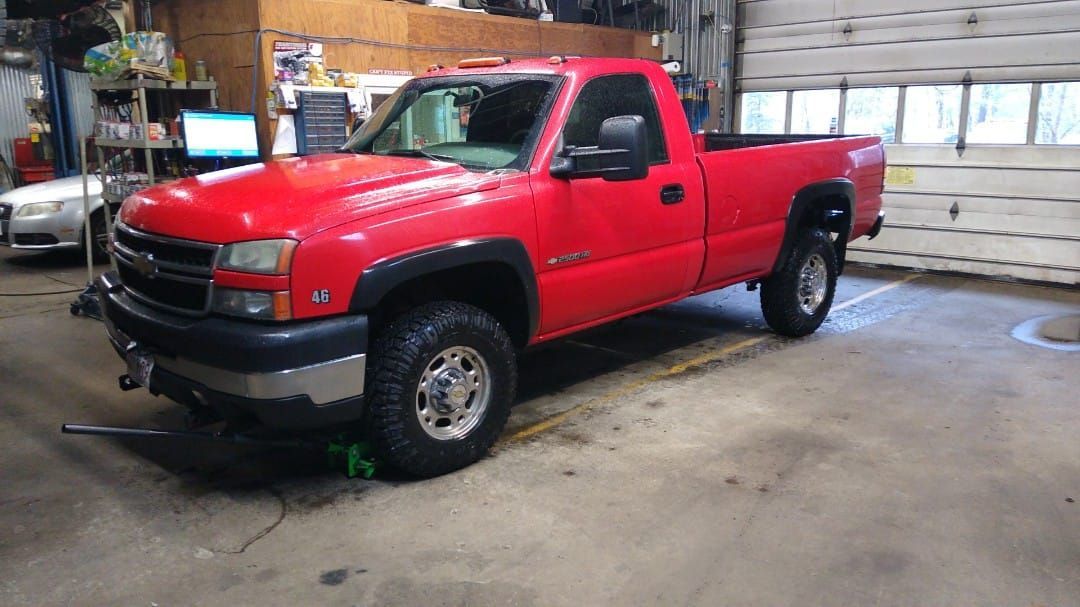 A red truck is parked in a garage next to a garage door.