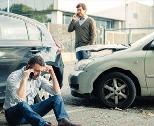 Two men calling car help assistance after an accident