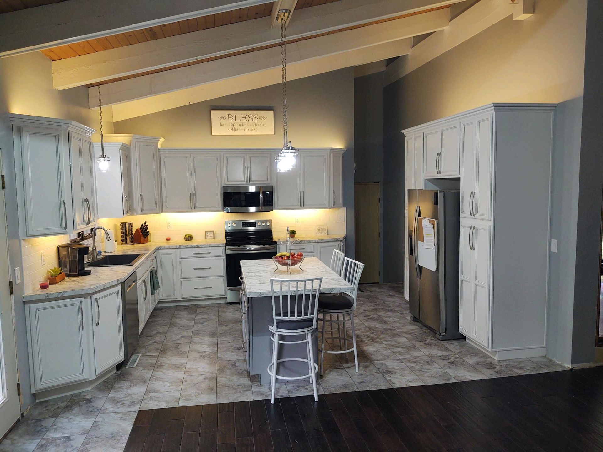 A kitchen with white cabinets , stainless steel appliances and a large island.