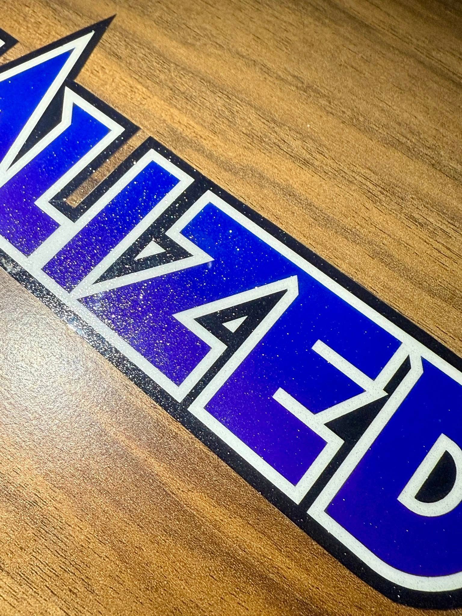 Blue and white glittery text on a wooden surface.