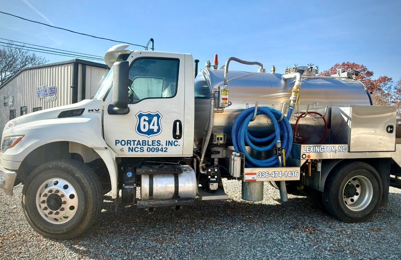 White truck with 64 Portables Inc. logo, carrying a large stainless steel tank, parked outside.