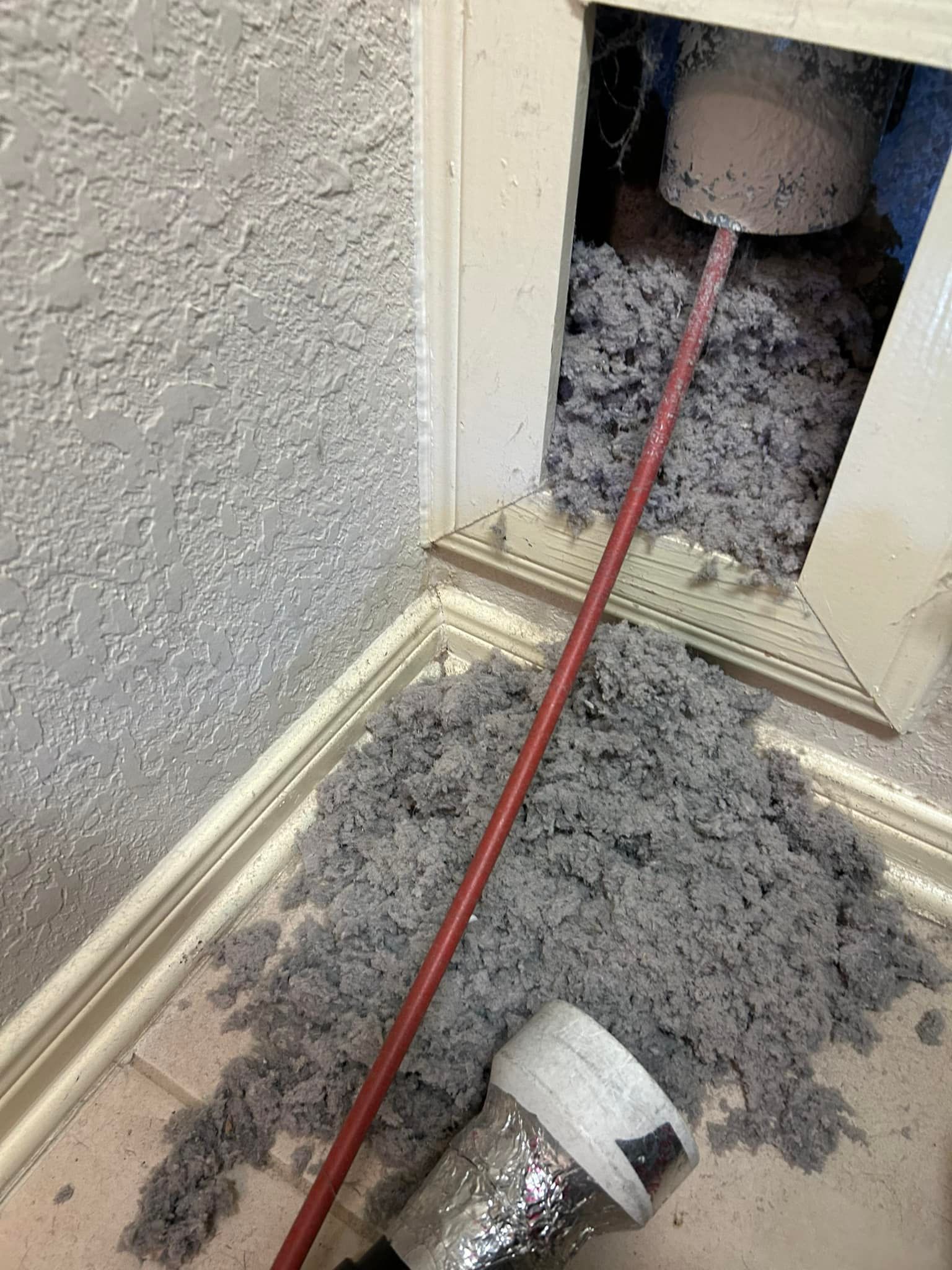 A vacuum cleaner is being used to clean a duct in a room.