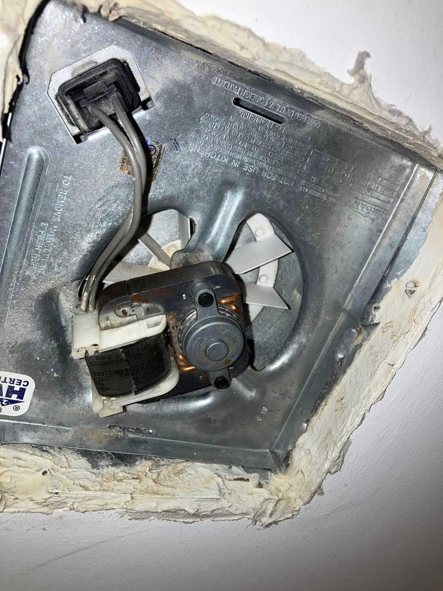 A close up of a fan in a hole in the ceiling.