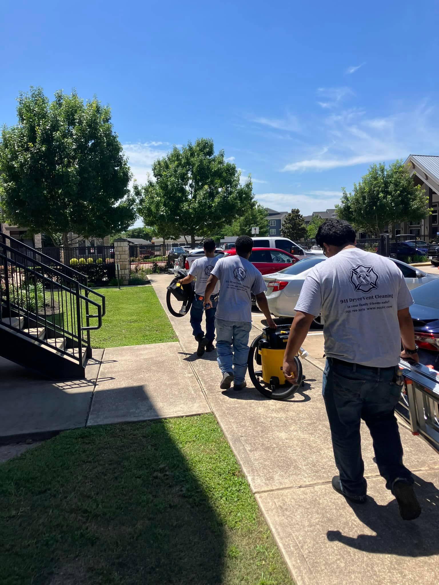A group of men are walking down a sidewalk carrying a vacuum cleaner.
