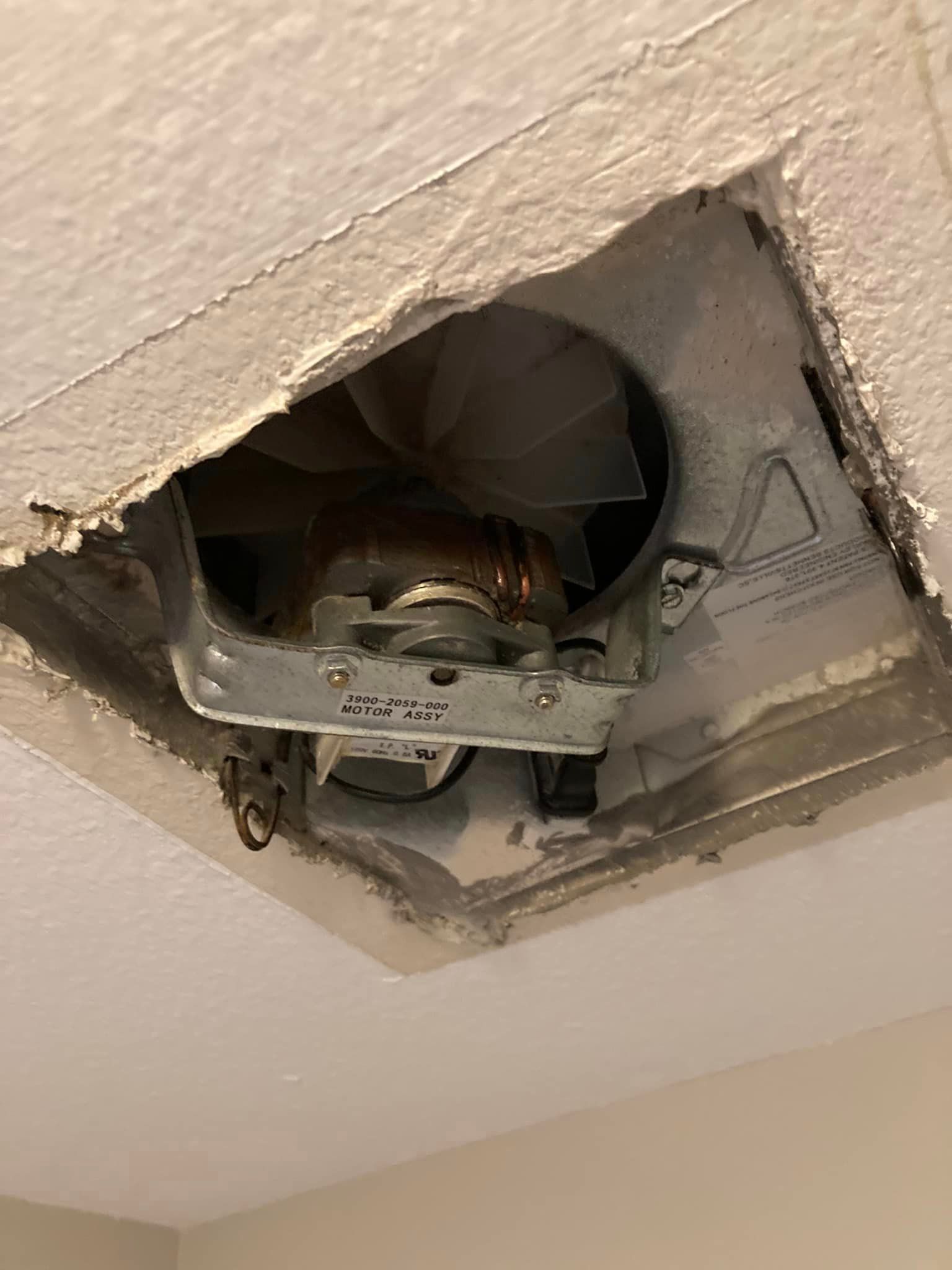 A fan is coming out of a hole in the ceiling.
