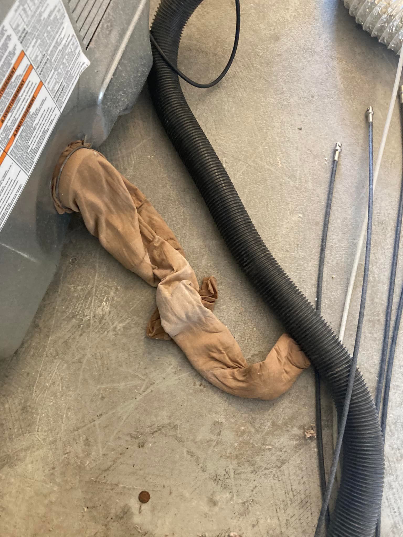 A hose is laying on the floor next to a vacuum cleaner.