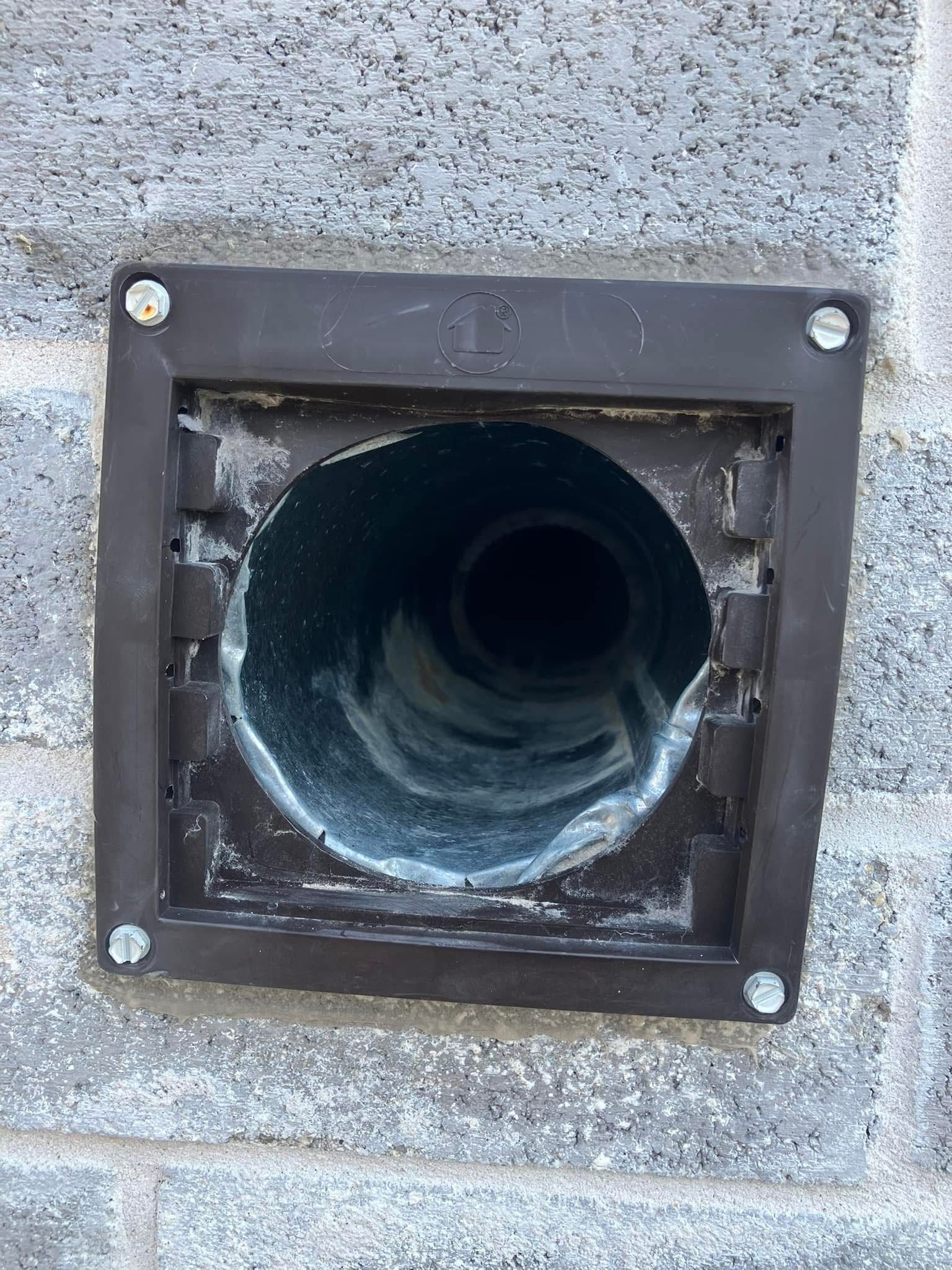 A hole in a brick wall with a metal pipe coming out of it.