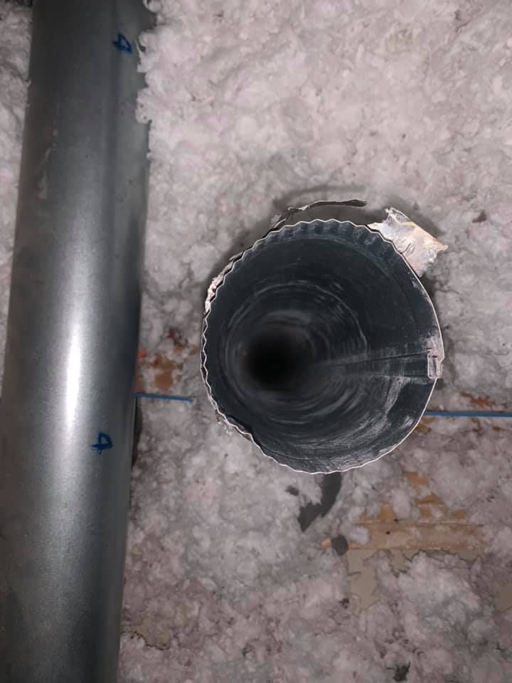A close up of a metal pipe in the attic.