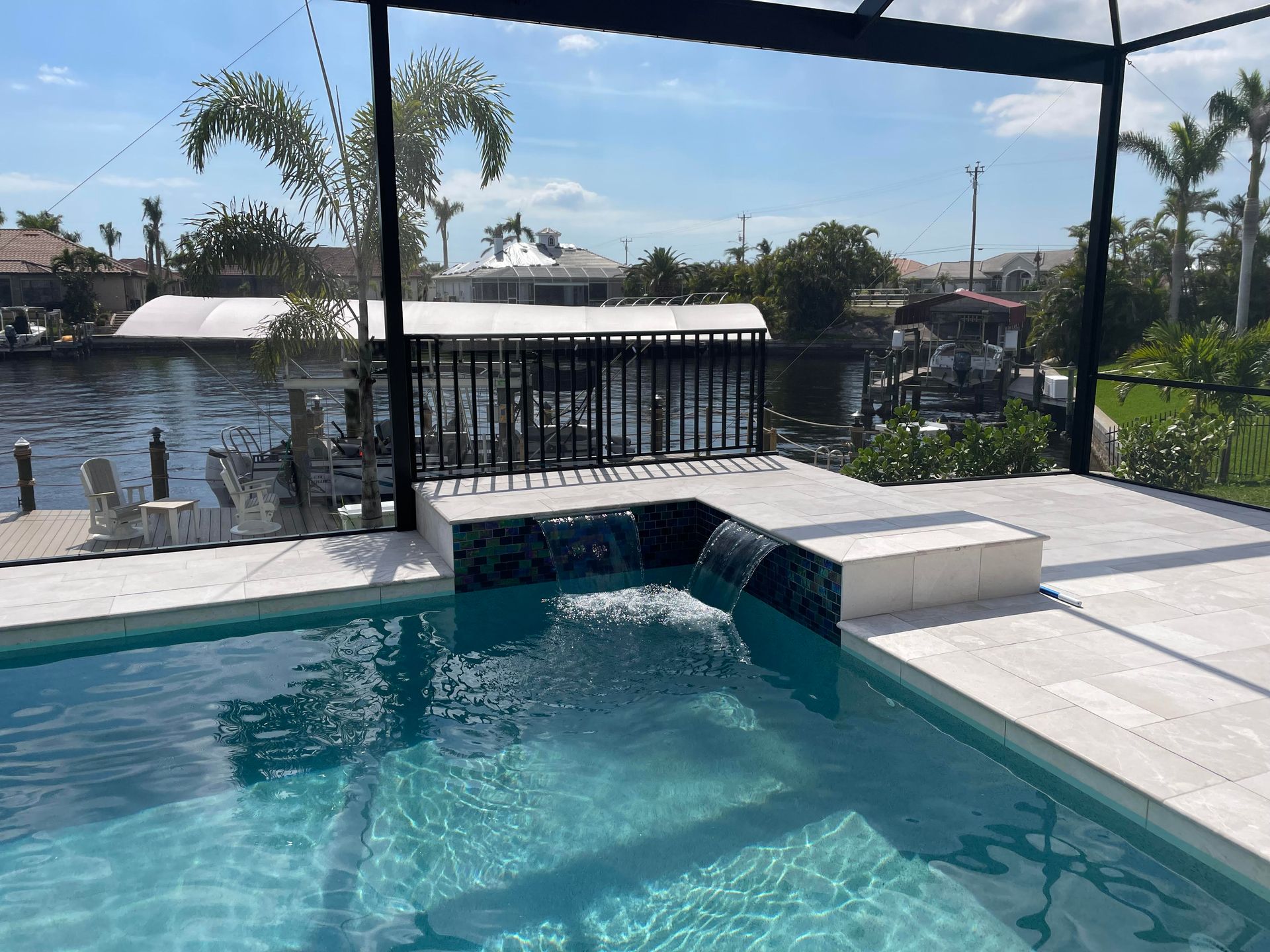 Backyard pool with turquoise water, white patio, and screened lanai overlooking a canal.