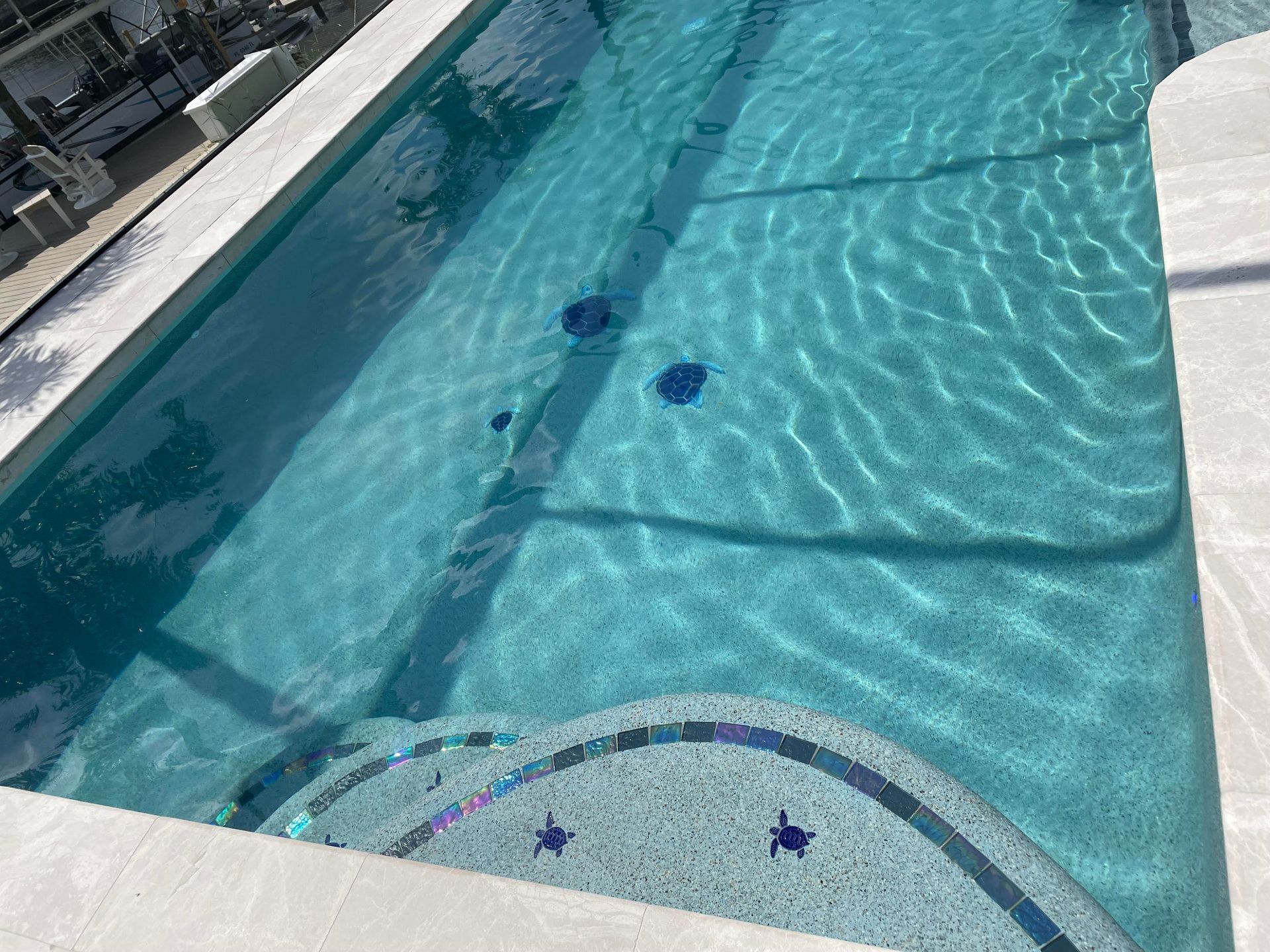 Outdoor swimming pool with clear blue water and a shallow end marked by star tiles at the bottom