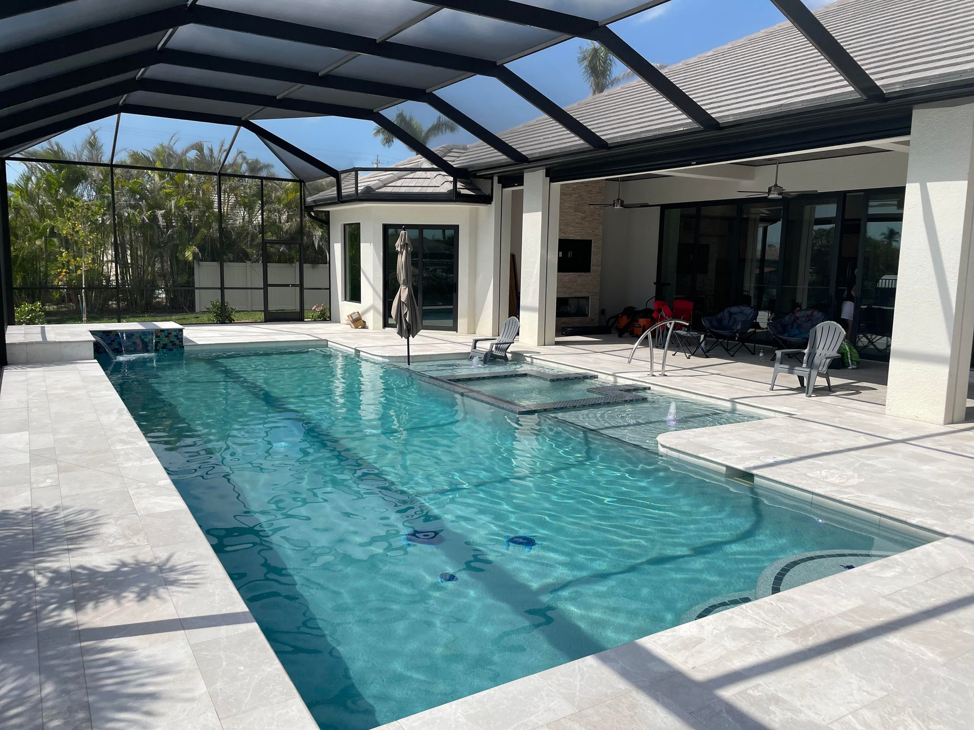 Covered backyard swimming pool with blue water and patio seating beside a screened enclosure