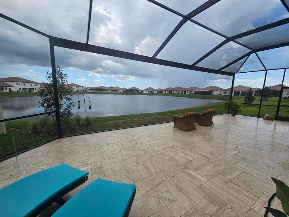 Patio with turquoise lounge chairs overlooking a lake, lawn, and homes under a cloudy sky