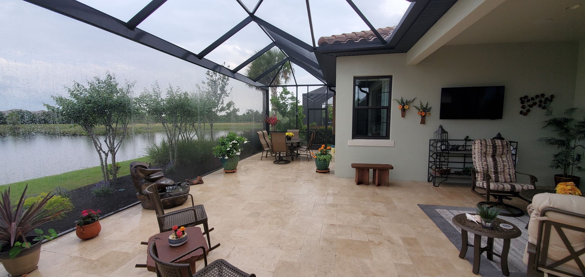 Screened-in patio with tan tile floor, white walls, seating, and a lake view beyond the mesh enclosure