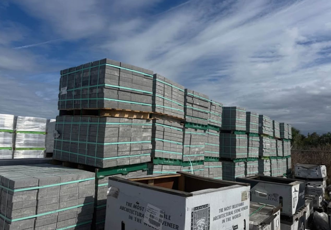 Stacks of wrapped pallets in an outdoor warehouse under a cloudy sky