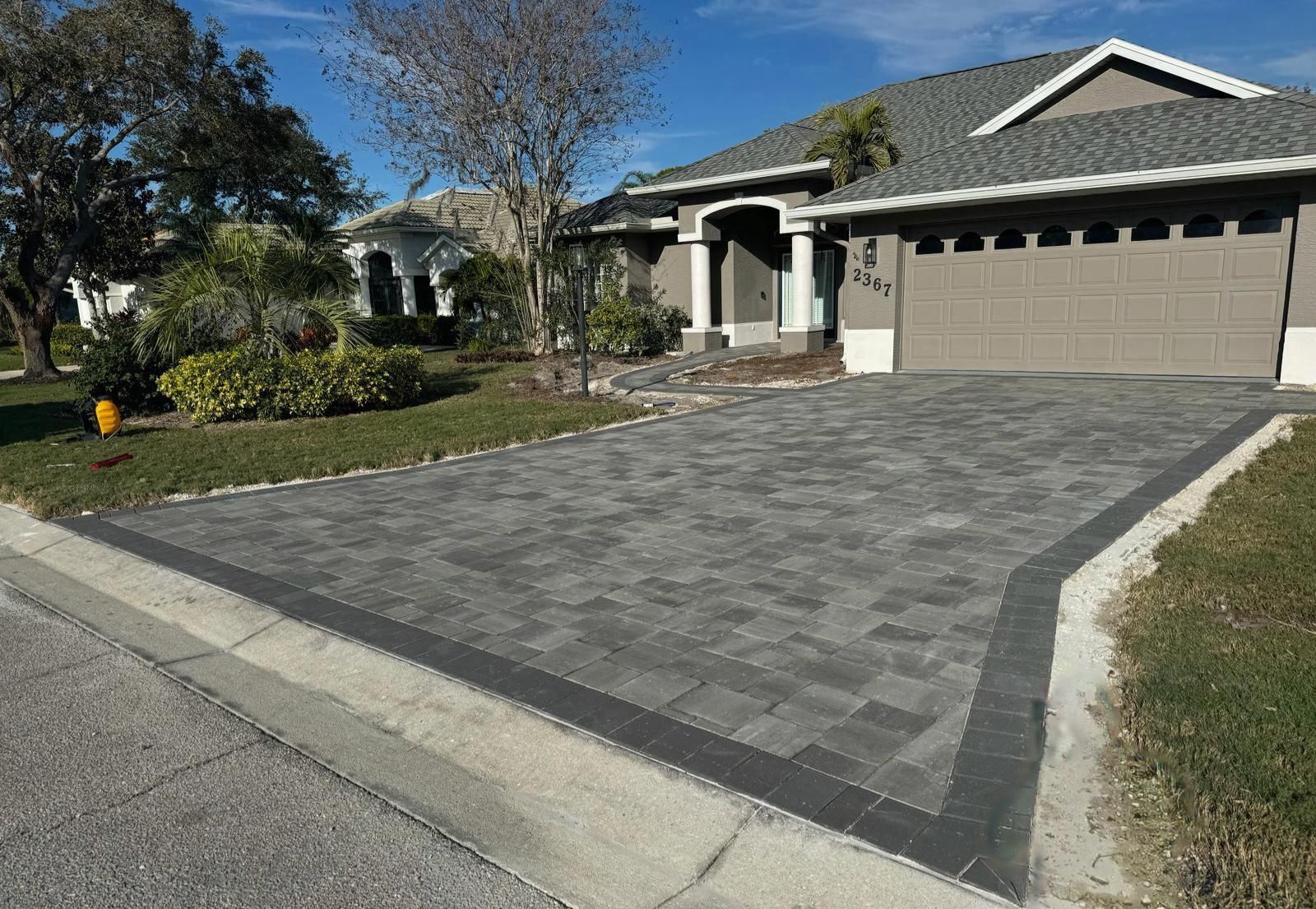 Modern home driveway with gray pavers and a two-car garage on a sunny day
