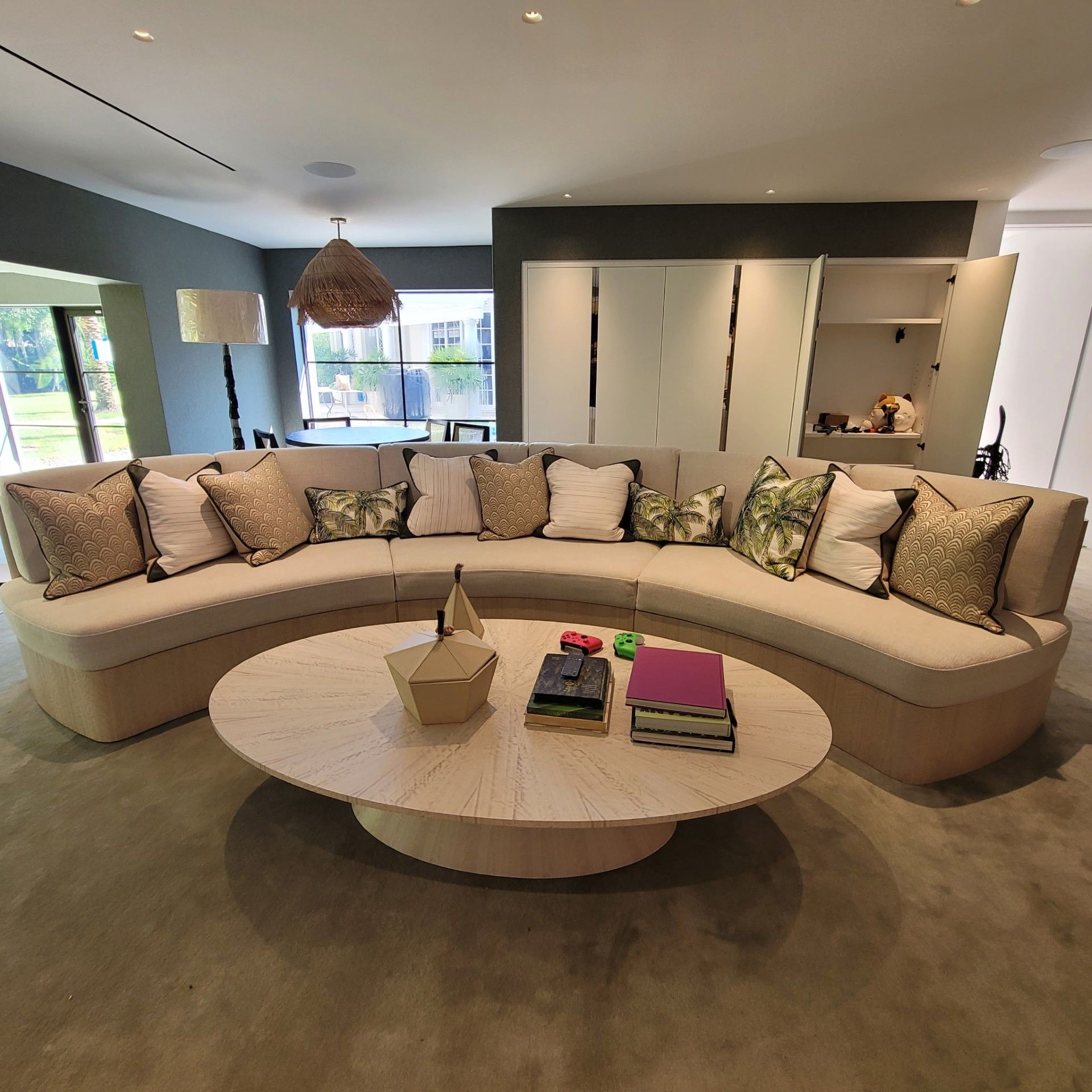 Modern living room with white sectional sofa, large windows, and hardwood floors.