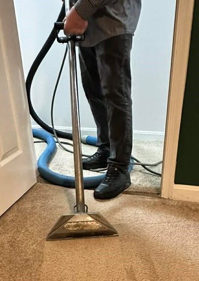 Person cleaning carpet with a professional machine in a doorway.