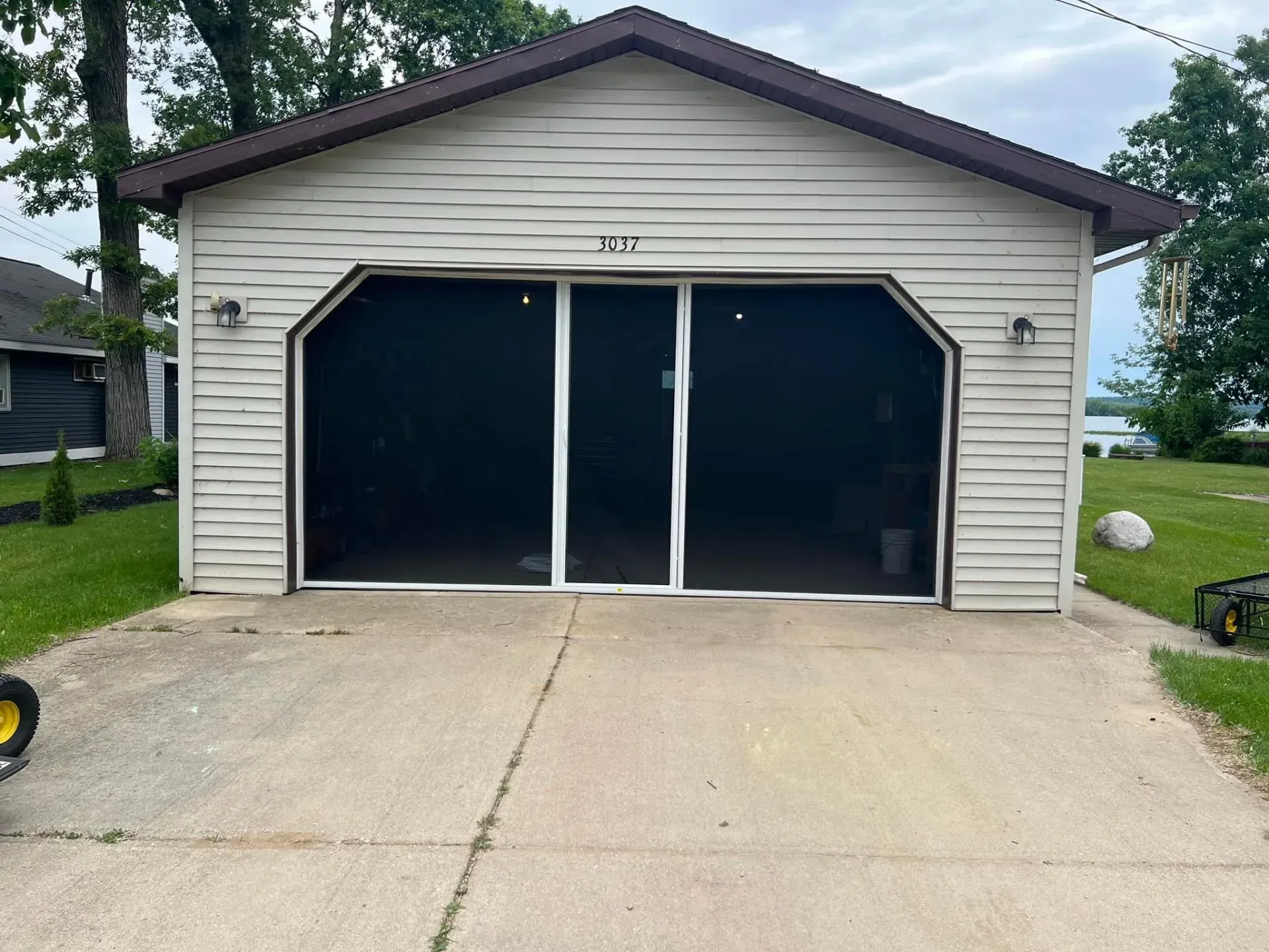 Two-car garage with beige siding, dark doors, and a concrete driveway.