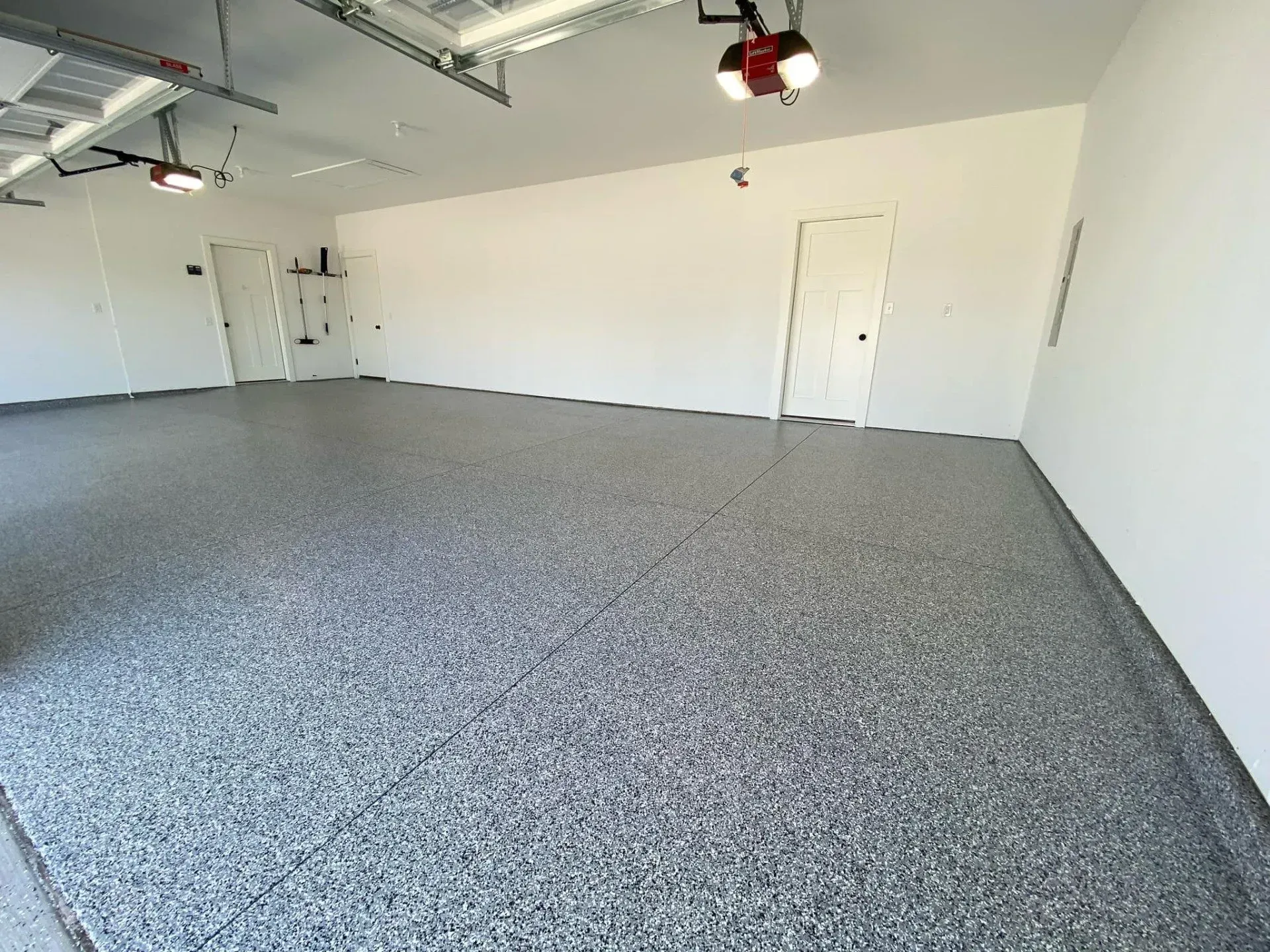 Empty white garage with gray speckled floor and overhead lights