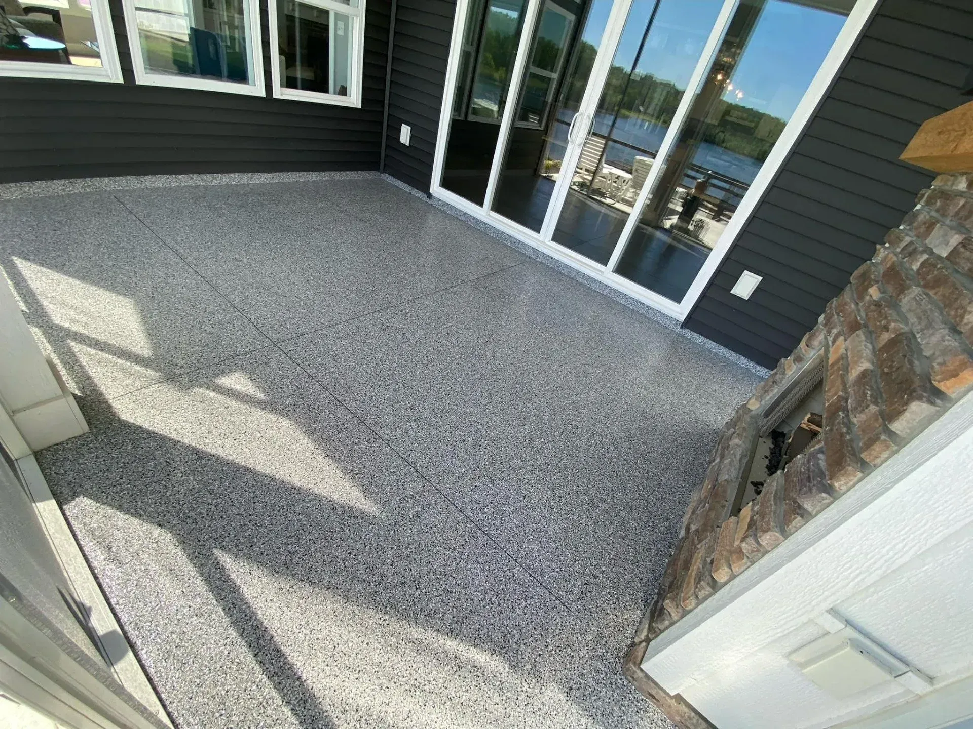 Covered patio with gray pebble flooring, glass doors, and stone accent wall
