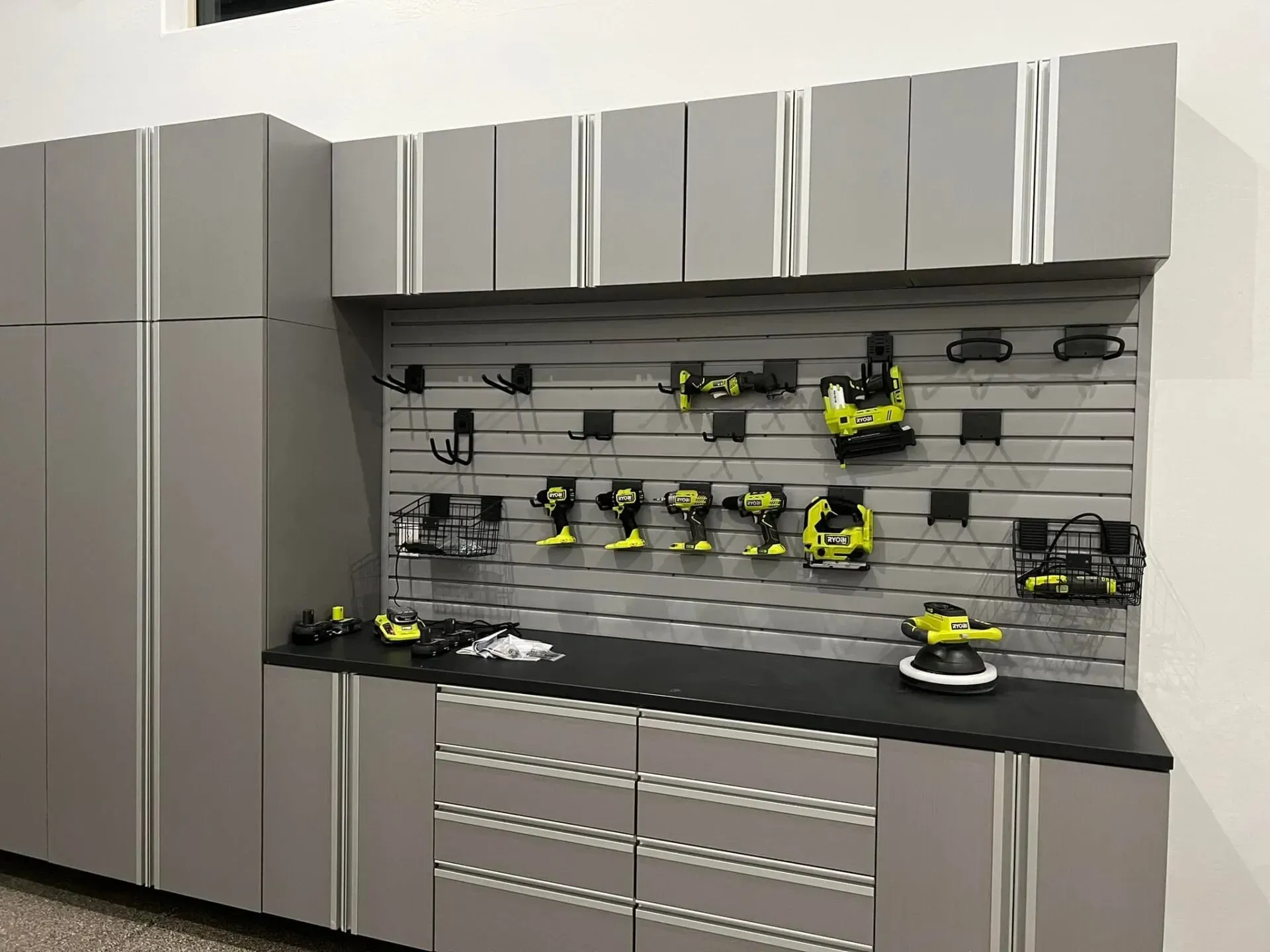 Gray garage cabinets with slatwall-mounted power tools and tool storage countertop