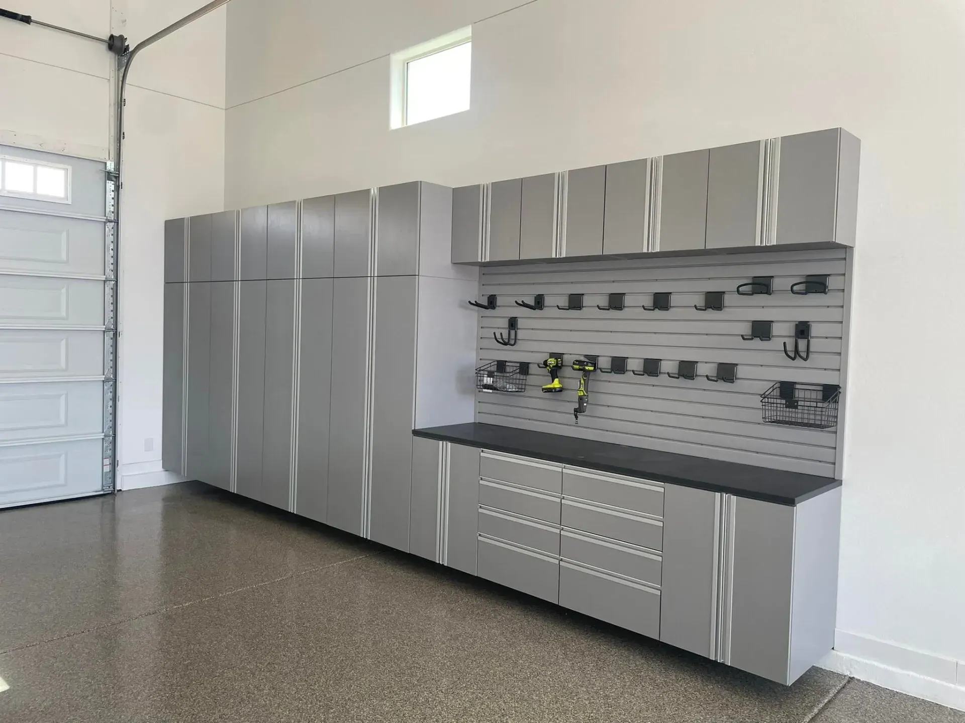 Garage with silver storage cabinets, workbench, pegboard tools, and drawers along the wall