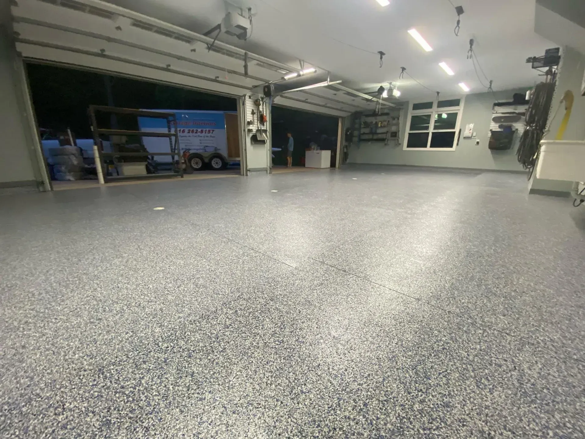 Empty garage with speckled gray floor, open bays, and overhead lights.