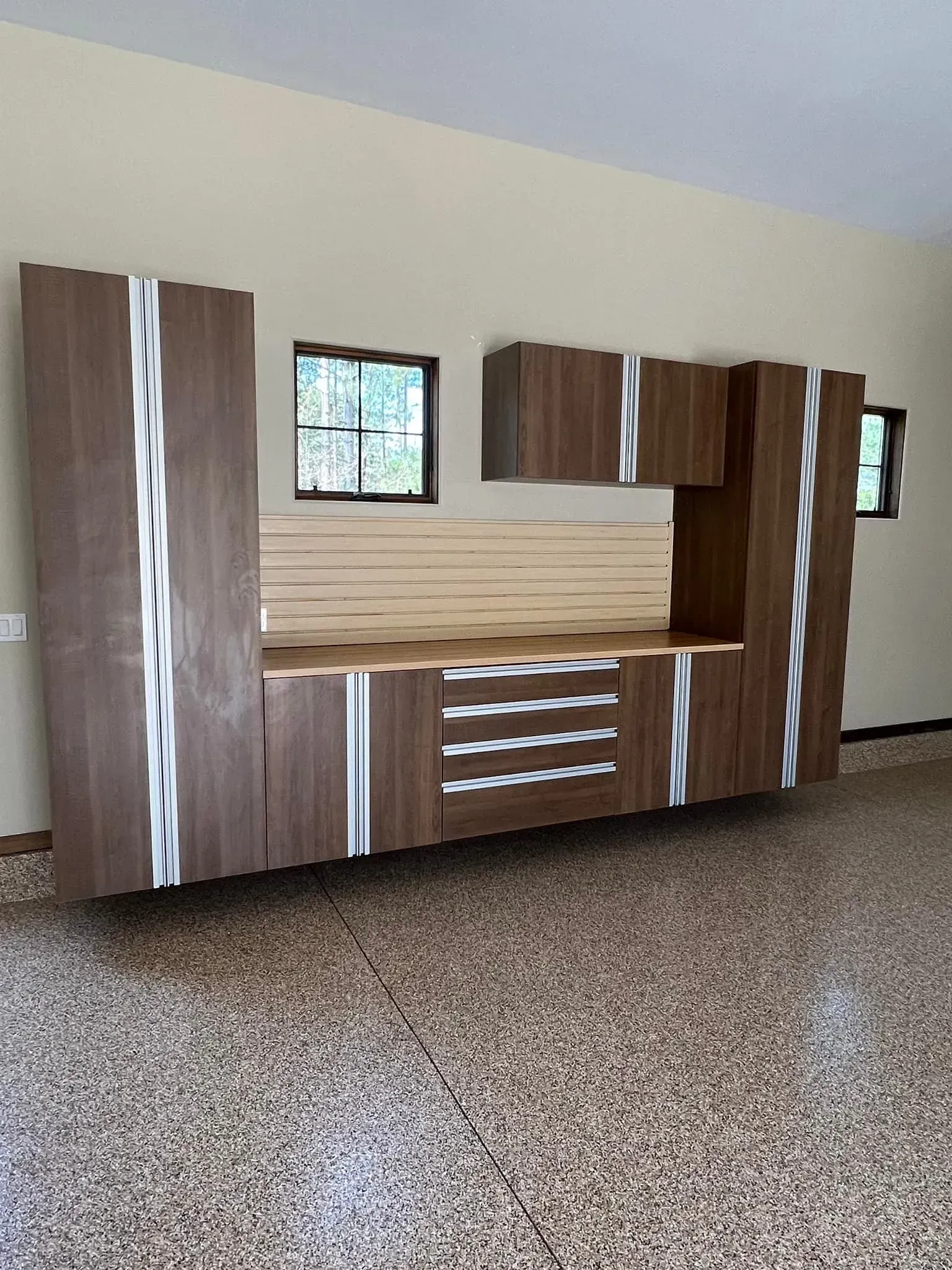 Wood-paneled wall unit with built-in shelves and drawers in an empty room