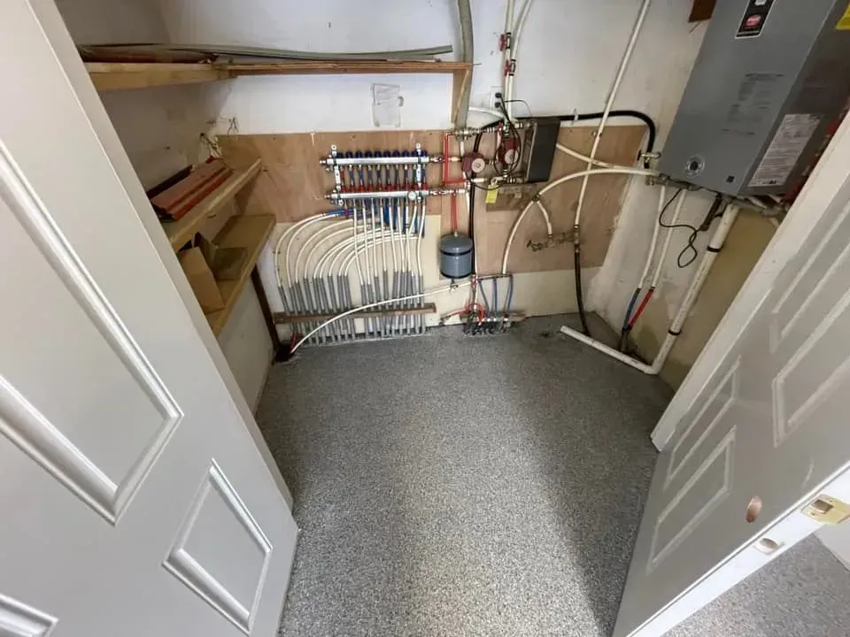 Small utility closet with shelves, pipes, water heater, and gray carpeted floor