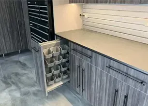 Kitchen with gray cabinets, beige countertop, white backsplash, and pull-out spice rack drawer.