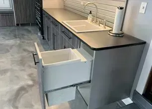 Kitchen with a pull-out trash drawer open beneath a countertop and sink.