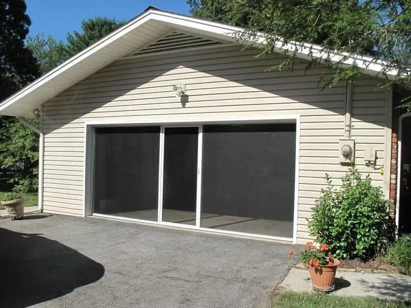 Detached beige garage with a double sliding door and a paved driveway in front