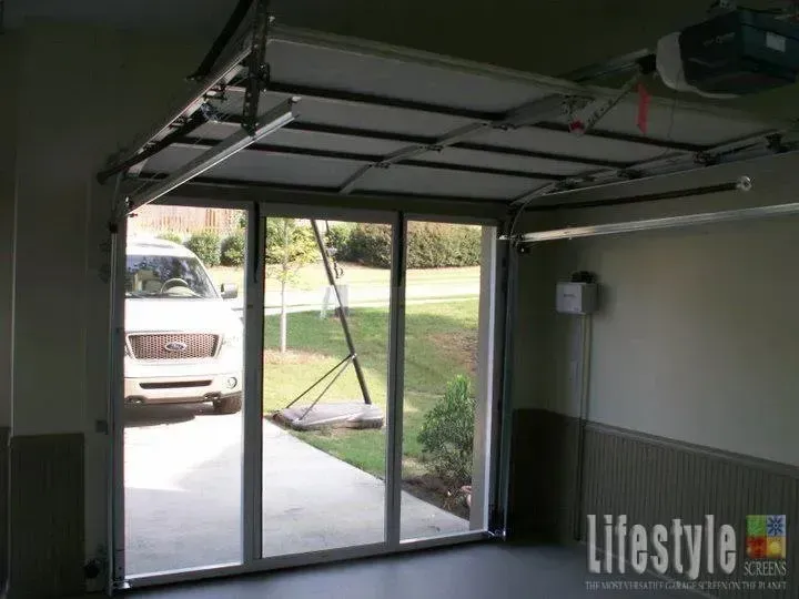 Open garage with sliding glass doors, driveway outside, and a parked SUV visible through the opening.