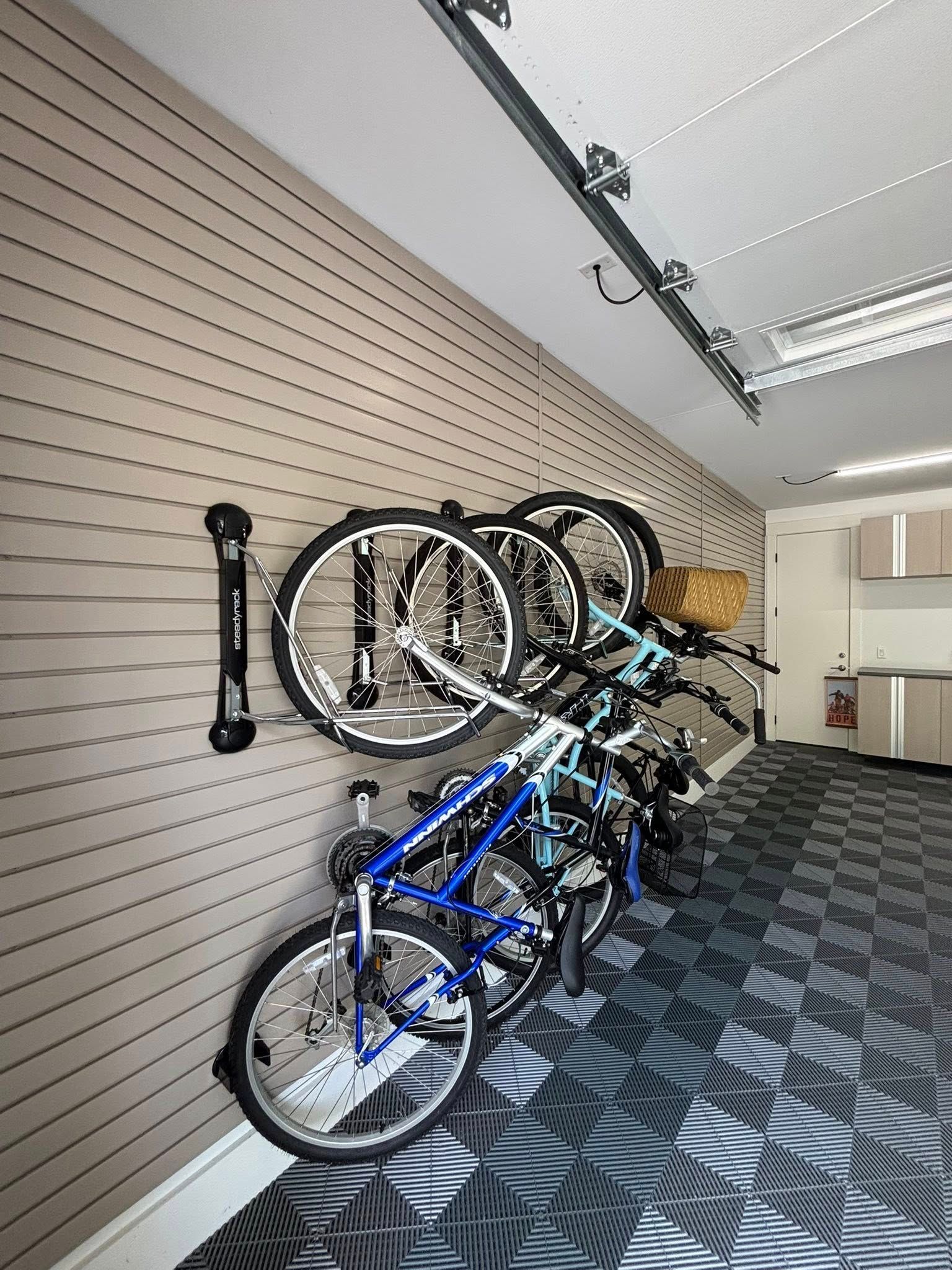 Bikes stored on wall-mounted racks in a hallway with patterned carpet and overhead lights