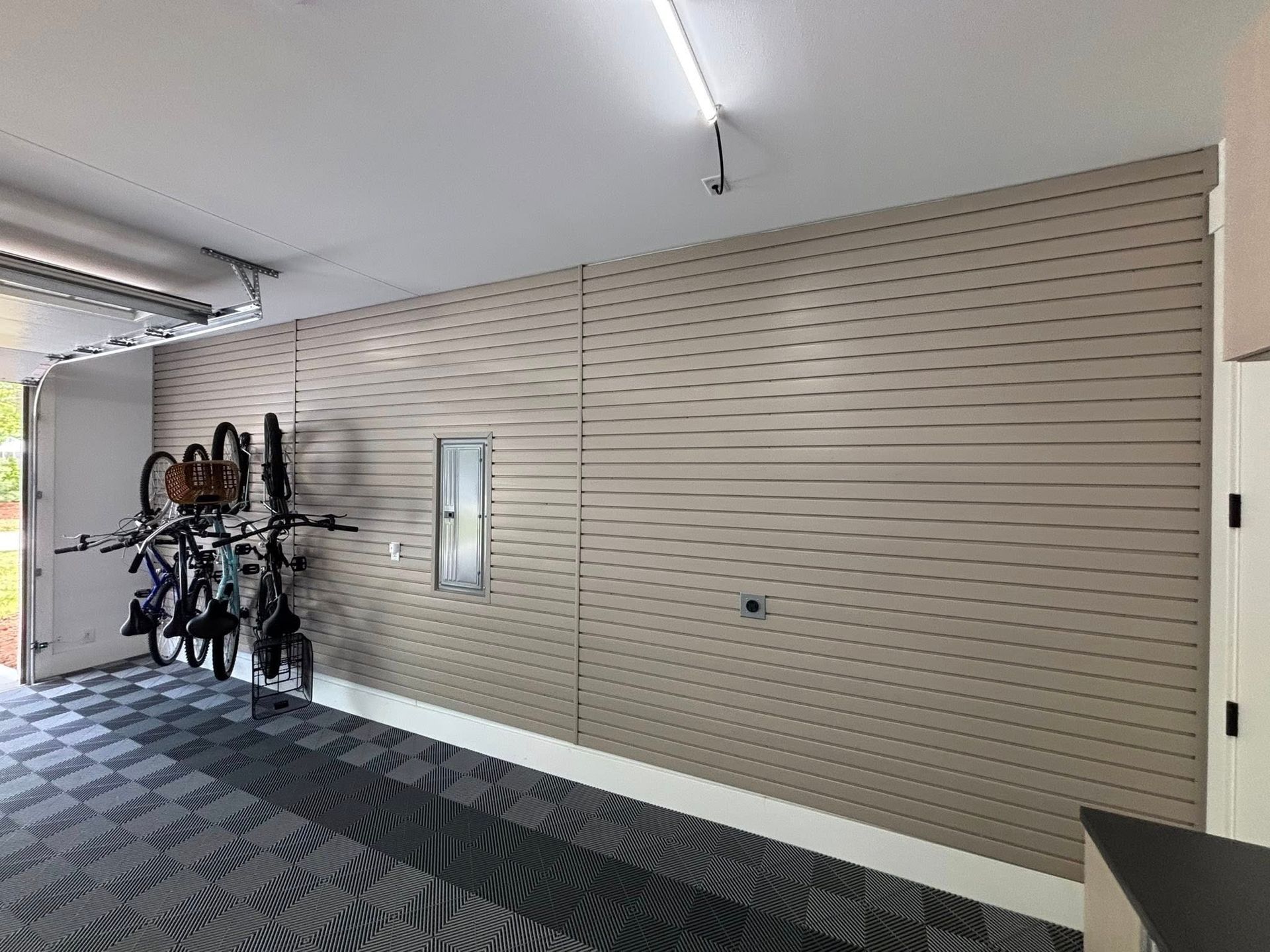 Indoor hallway with beige slat wall, carpet, wall mirror, and a rack of bicycles near an open doorway