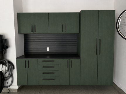 Green garage cabinets with black countertops and a slatted black backsplash against a white wall.