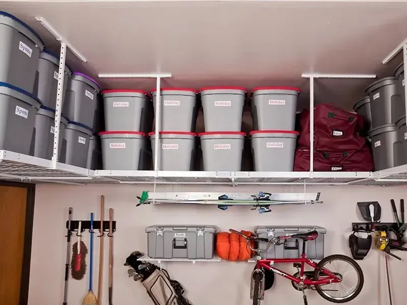 Garage shelf with gray storage bins, tools, and a red bicycle hanging below.