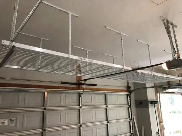 Empty garage interior with overhead metal storage racks and a closed garage door